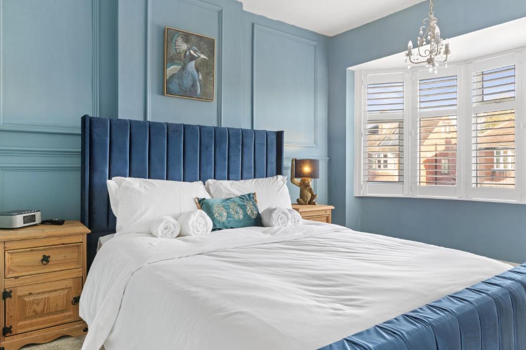 um quarto azul com uma grande cama com lençóis brancos em Lovely 2 Bedroom House with Parking em Loughborough