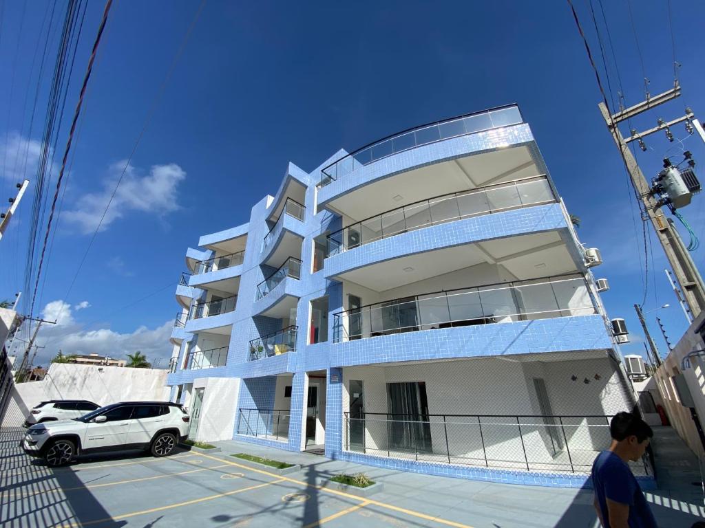 Fort Poseidon, venha desfrutar do conforto de sua casa a 700 metros da praia do Atalaia na rua do Atalho, apartamento mobiliado novo, duas suítes, mais banheiro social, varanda, sala de estar e jantar, lavanderia e cozinha, vista para as dunas e praia في سالينوبوليس: سيارة بيضاء متوقفة أمام مبنى