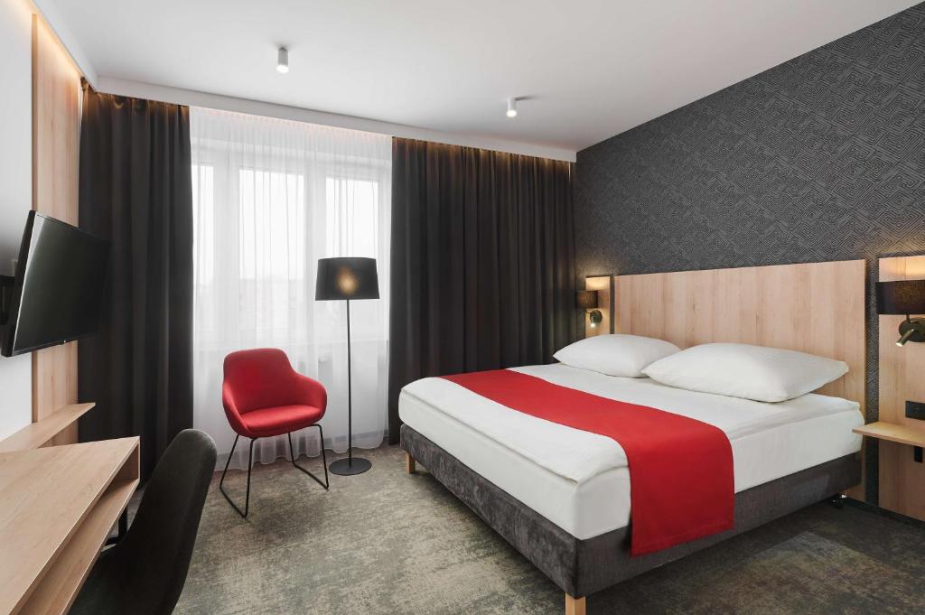 a hotel room with a bed and a red chair at Best Western Plus Hotel Rzeszow City Center in Rzeszów