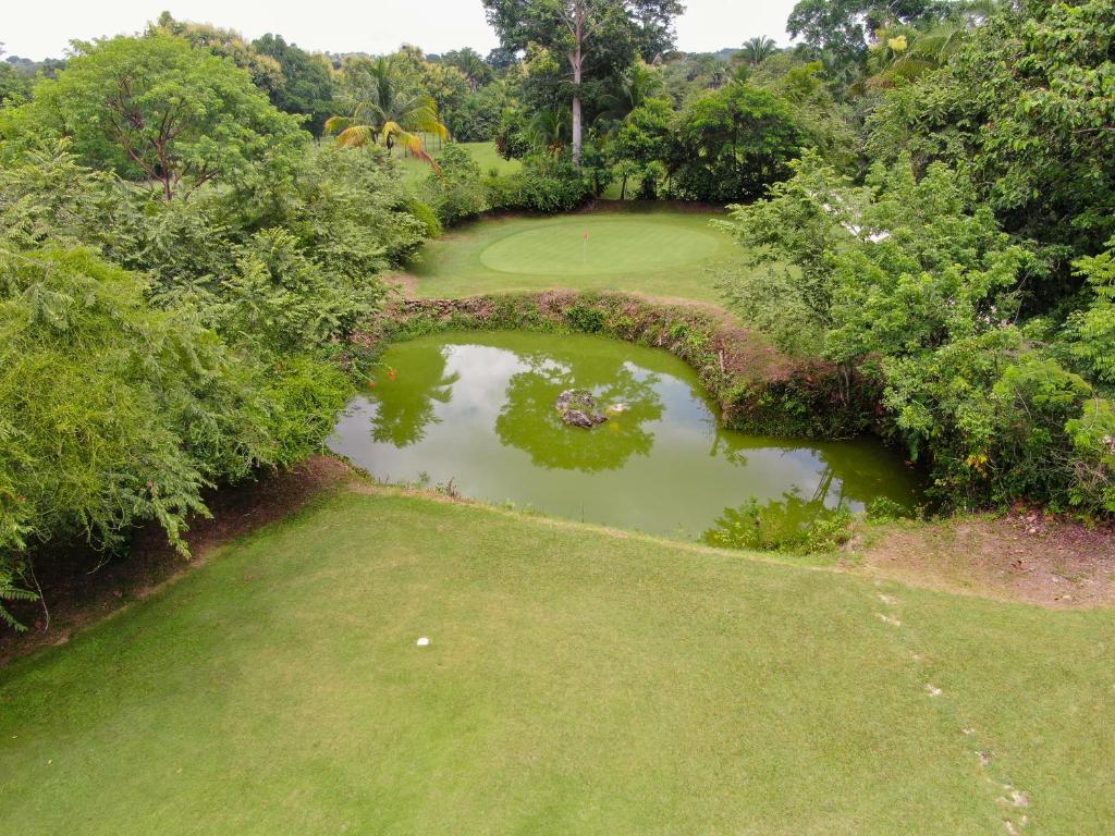 an overhead view of a golf course with a bridge over a pond at Roaring River Golf & Accommodations in Belmopan