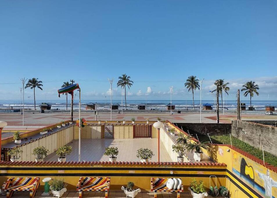 uma vista para uma praia com palmeiras e para o oceano em Apartamento pé na areia de frente para o mar em Mongaguá