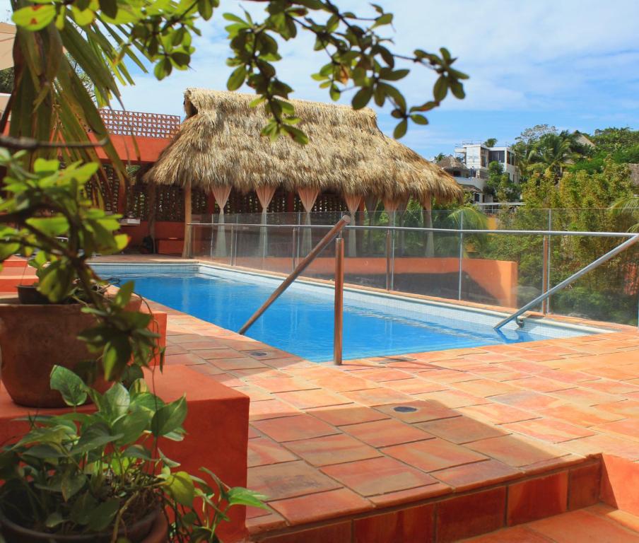 a swimming pool with a straw umbrella and a building at Casa Pepe in Sayulita