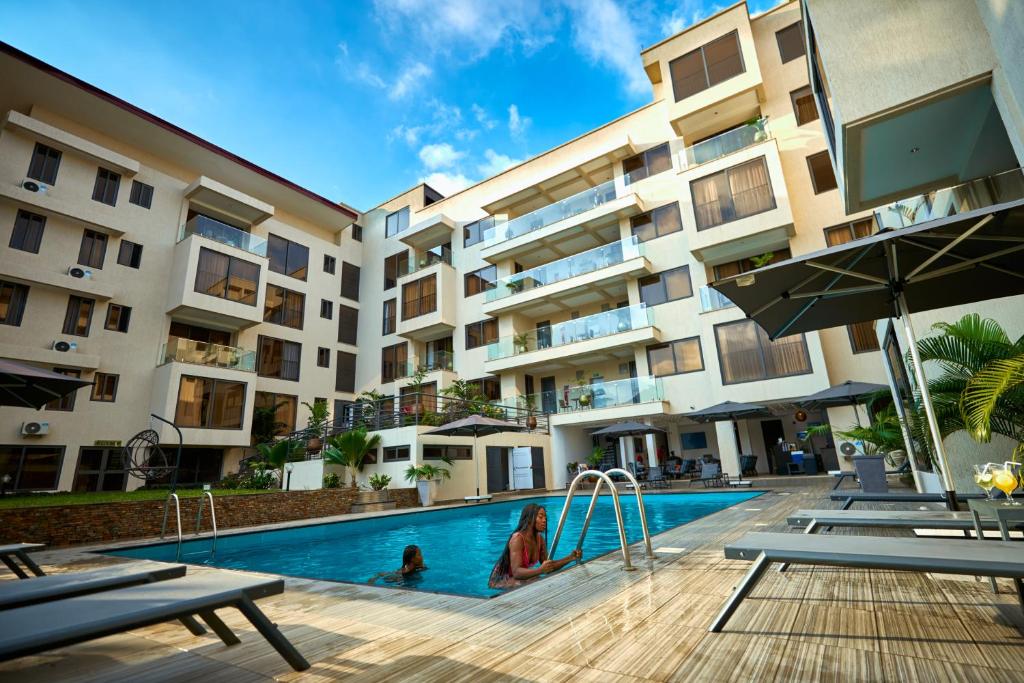 a hotel with a swimming pool in front of a building at Veronique Heights in Kumasi