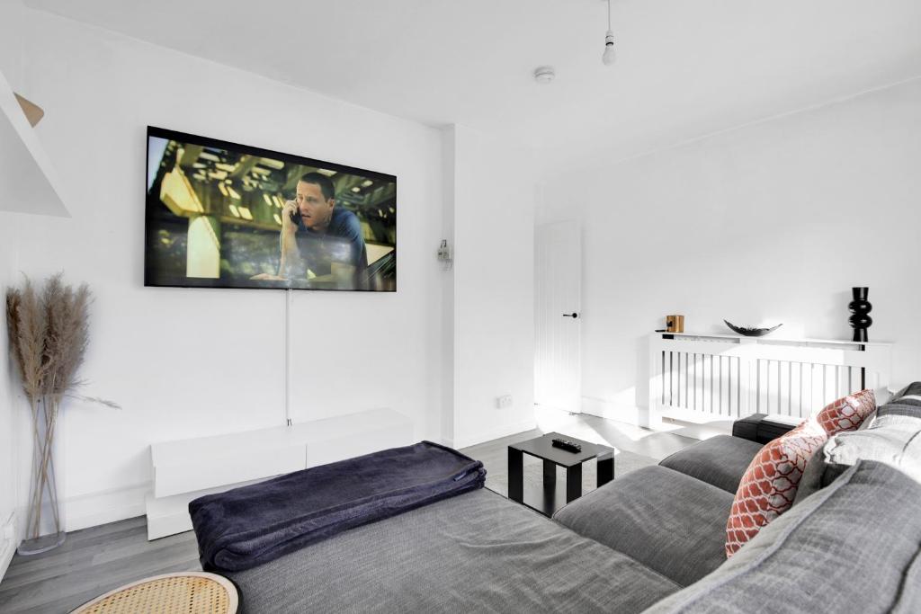 a living room with a couch and a tv on the wall at Peckham apartments by APS in London