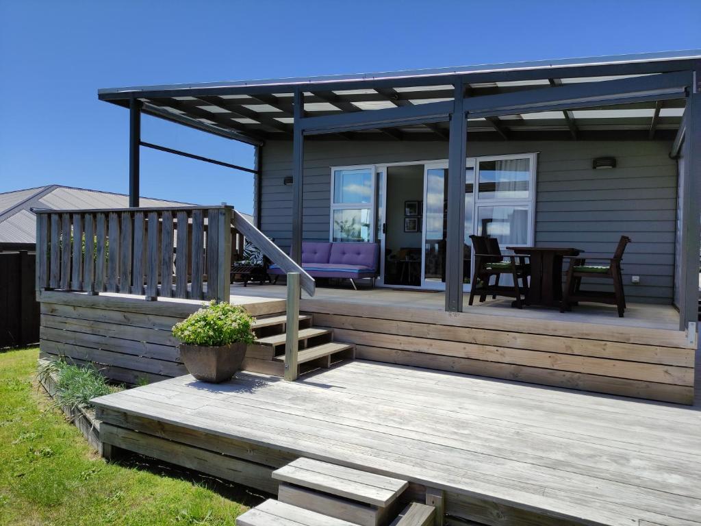 ein Haus mit einer Holzterrasse mit einem Tisch in der Unterkunft Modern House near Motuoapa Tongariro Crossing fishing skiing in Turangi