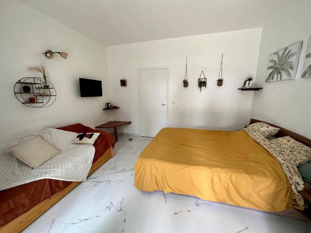 Folle AnseにあるKaz' Kiki Cocoのベッドルーム1室(ベッド2台、壁掛けテレビ付)