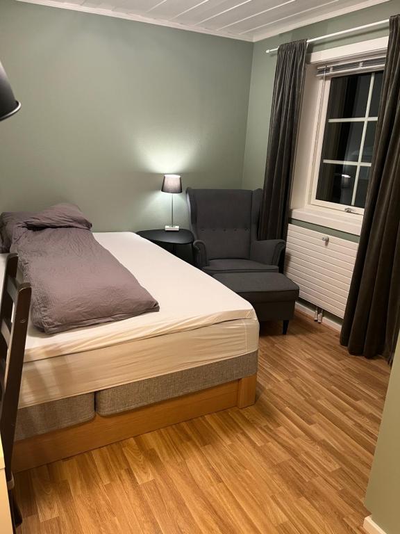 um quarto com uma cama, uma cadeira e uma janela em Koselig rom i rolige omgivelser em Åmot