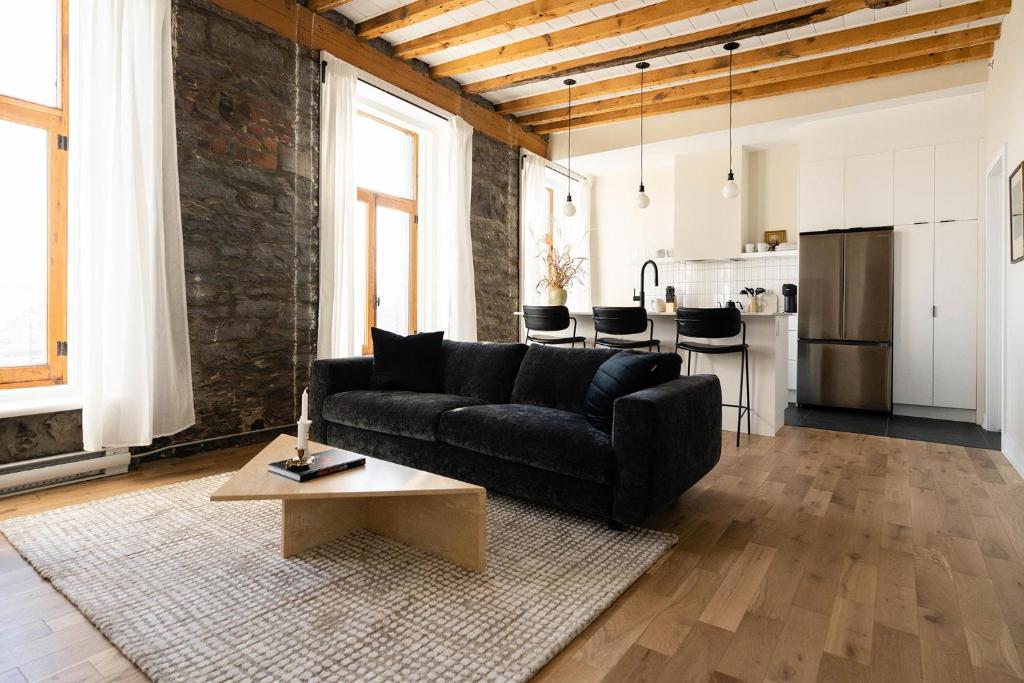 a living room with a black couch and a table at Maison Place Royale in Montréal