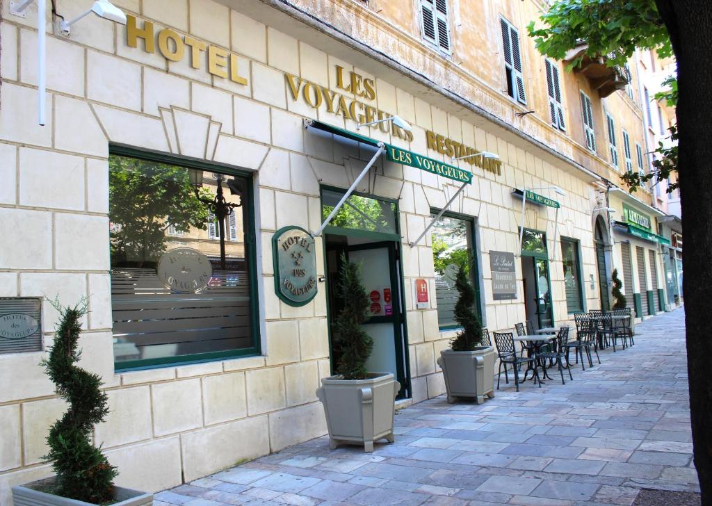 ein Geschäft vor einem Gebäude mit Tischen und Stühlen in der Unterkunft Hôtel Les Voyageurs in Bastia