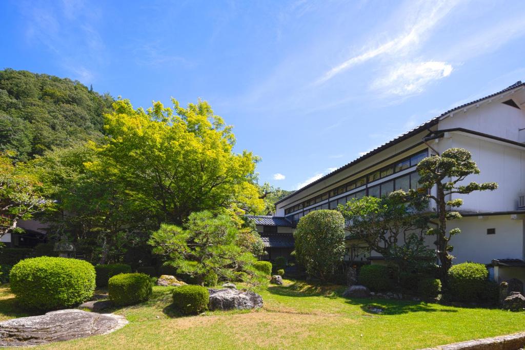 um edifício com um jardim em frente em Tokiwa Bekkan em Toyooka