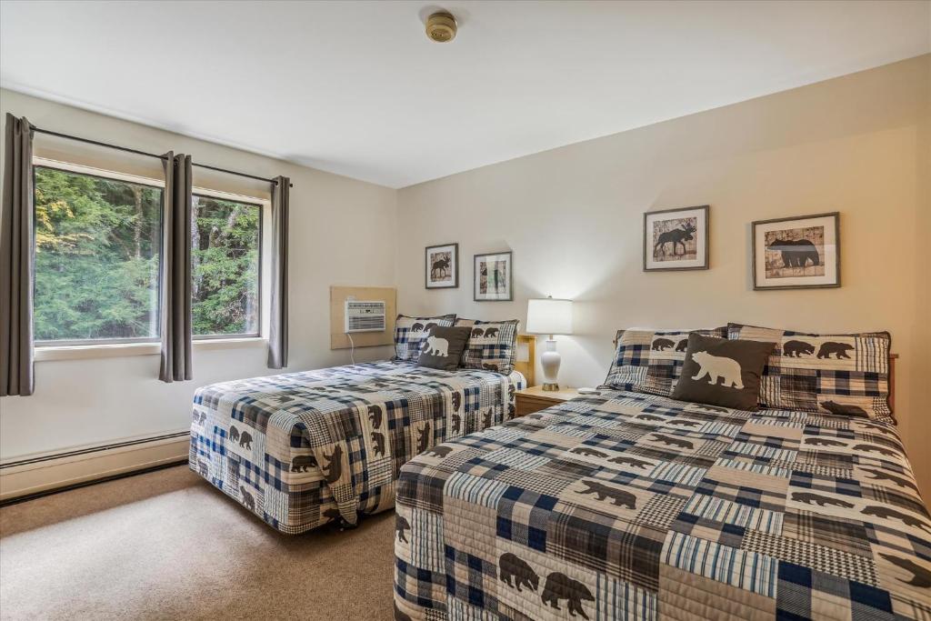 two beds in a room with two windows at Cedarbrook Two Double bed Standard Hotel room 217 in Killington