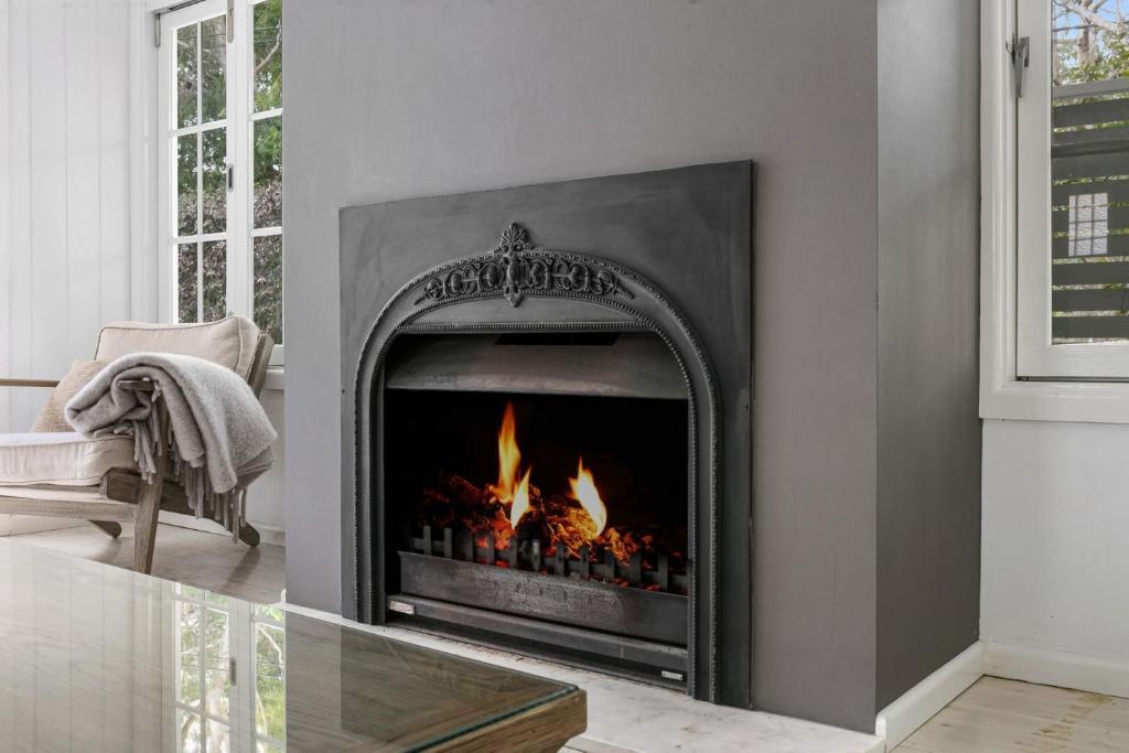 a fireplace in a living room with flames in it at Pearl House By Coast Holidays in Pearl Beach