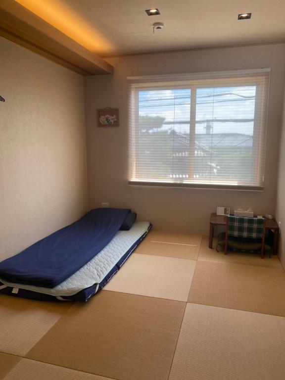 una camera con letto, finestra e tavolo di ゲストハウス奈良庵 Nara An a Nara