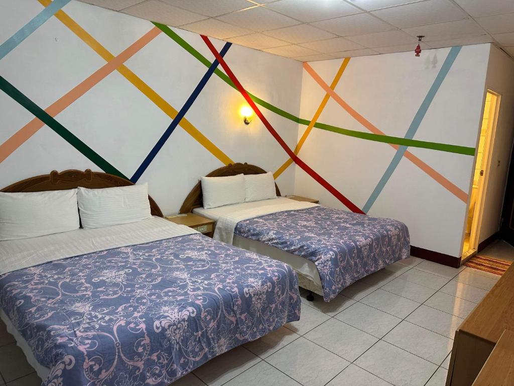 a room with two beds and a colorful wall at 知本溫泉小燕的家 in Wenquan