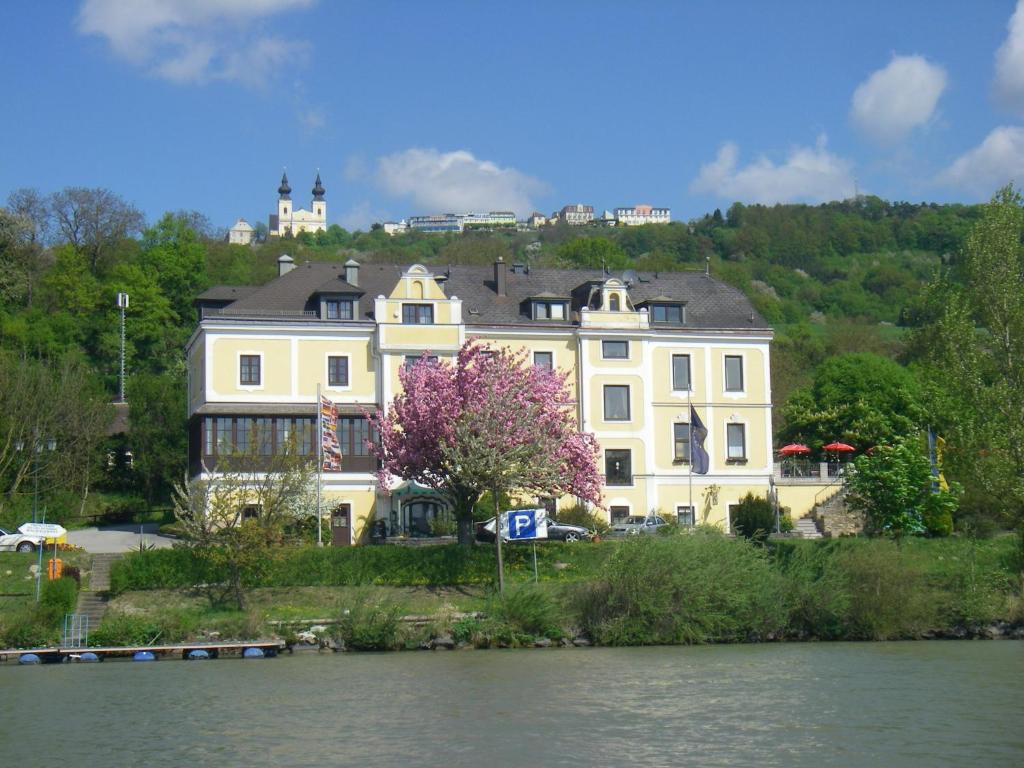 una gran casa blanca en una colina junto a un río en Donau-Rad-Hotel Wachauerhof en Marbach an der Donau