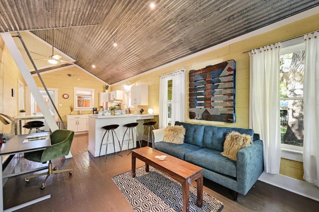 a living room with a blue couch and a kitchen at Peaceful Bungalow with Fenced Yard near Shops and Cafes in Austin