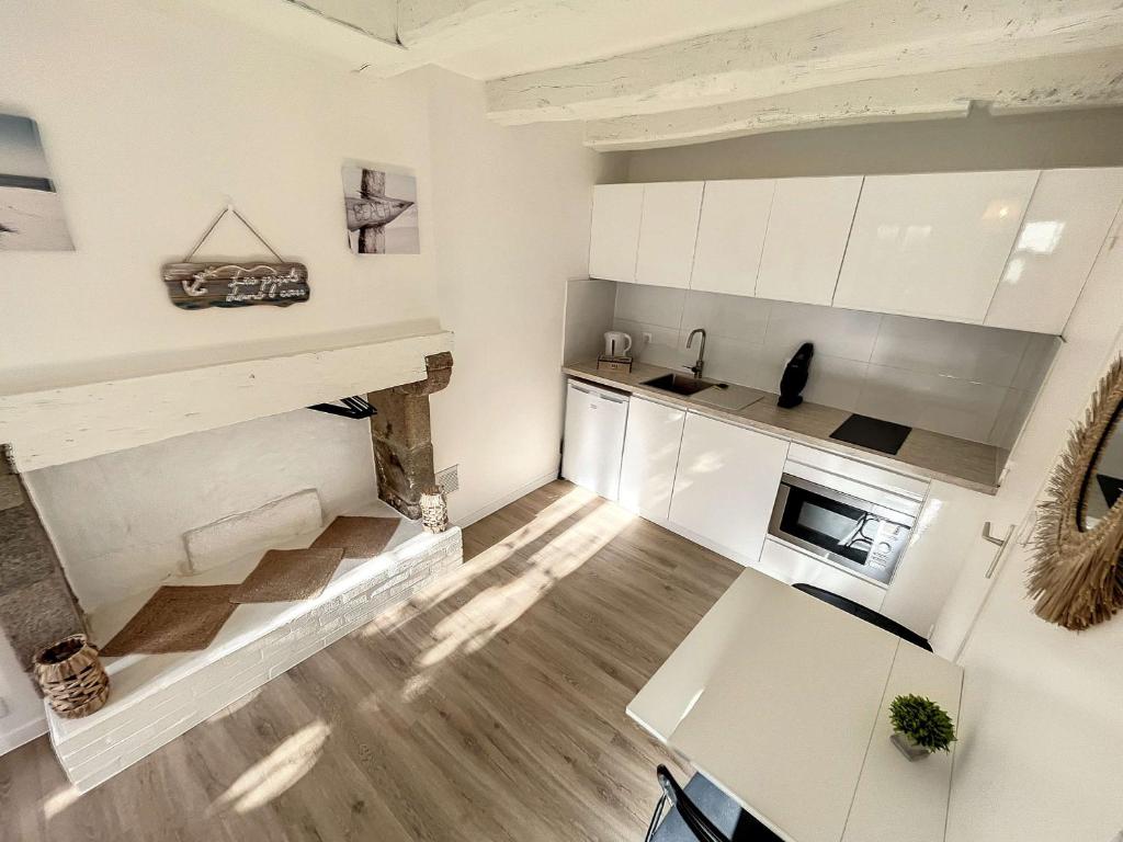a kitchen with white cabinets and a stone fireplace at Studio Granville, 1 pièce, 2 personnes - FR-1-361-526 in Granville