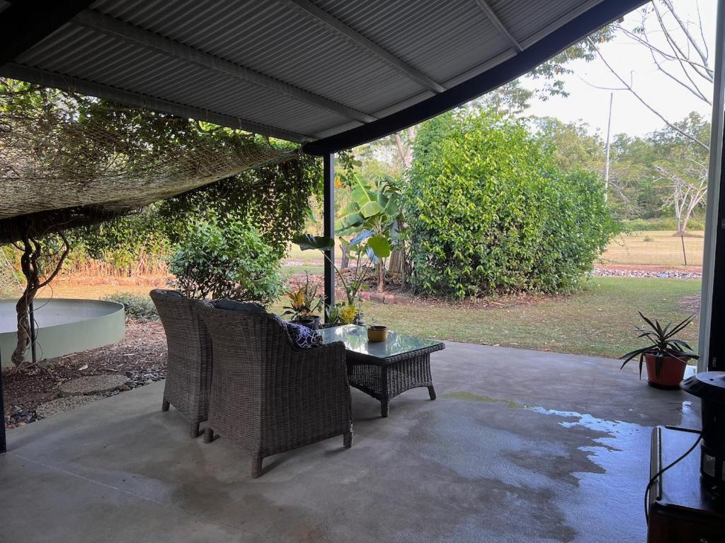 un patio con mesa y sillas bajo una sombrilla en Quiet Rural Retreat en Howard Springs