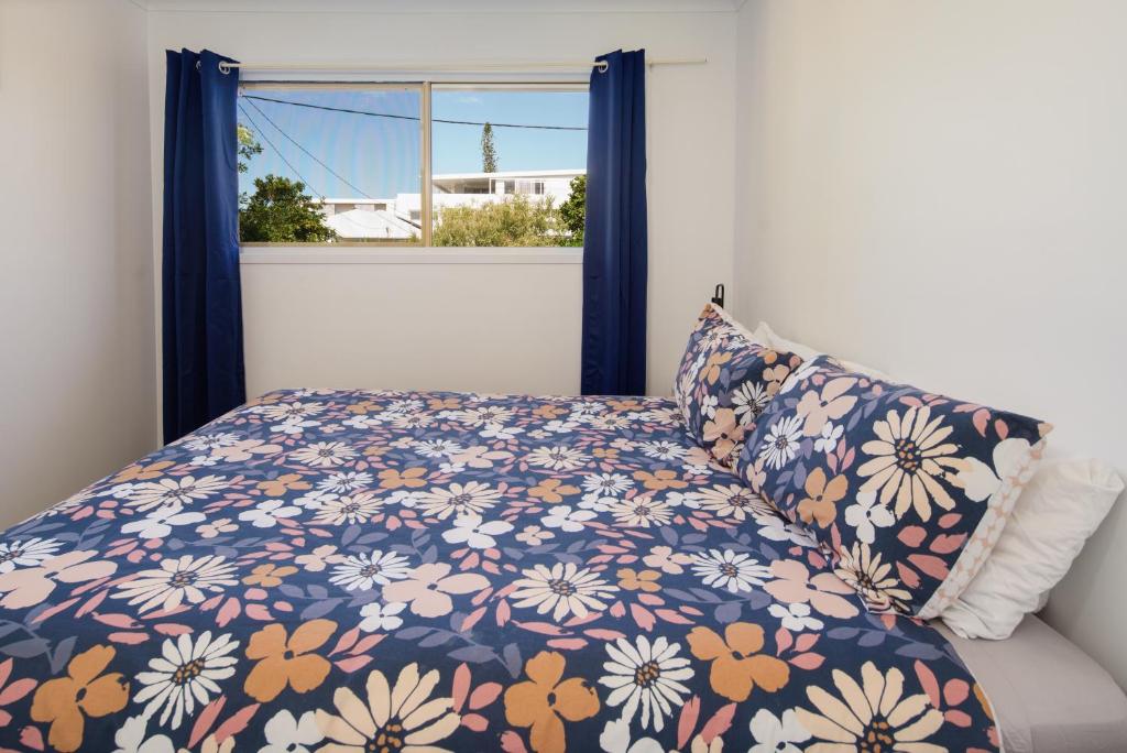 a bed with a floral bedspread and a window at Growder Court 3 - Coolum Beach QLD in Coolum Beach