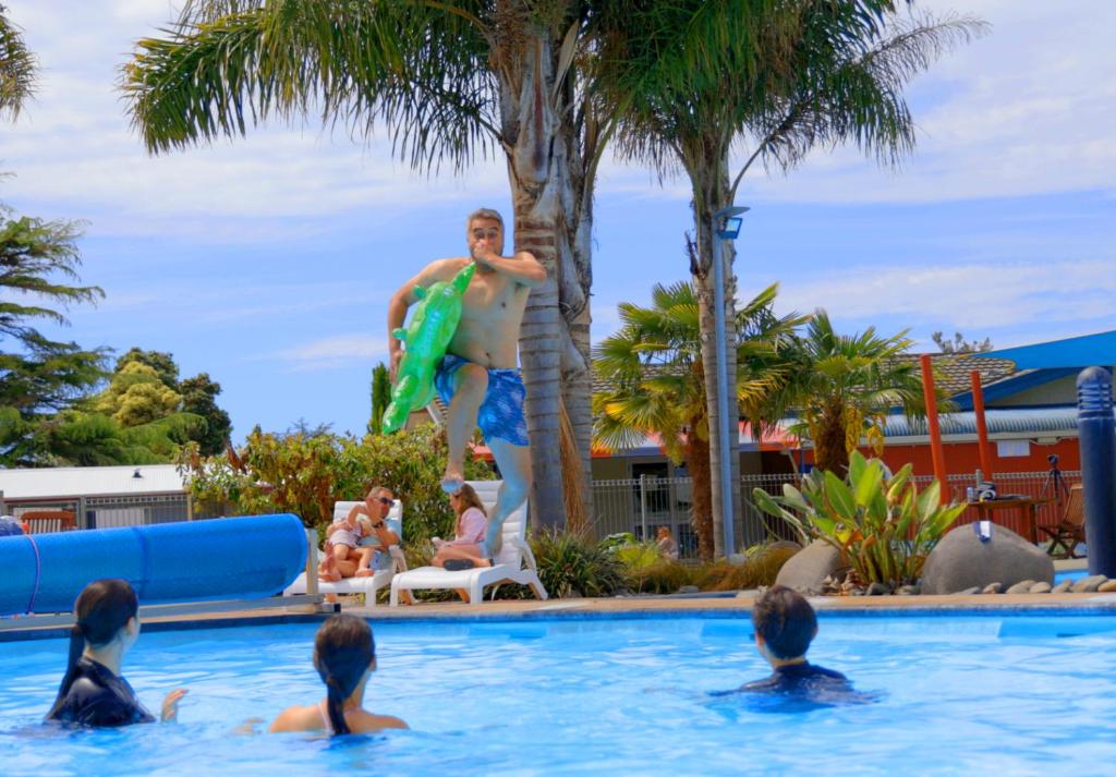 a man in a swimming pool with a surfboard at Kennedy Park Resort Napier in Napier