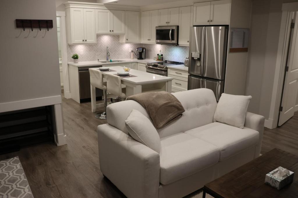 uma sala de estar com um sofá branco e uma cozinha em Golden Ears Nature's Delight em Maple Ridge