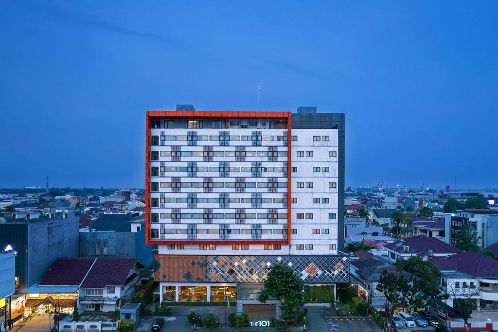 a tall white building with red trim in a city at THE 1O1 Palembang Rajawali in Palembang