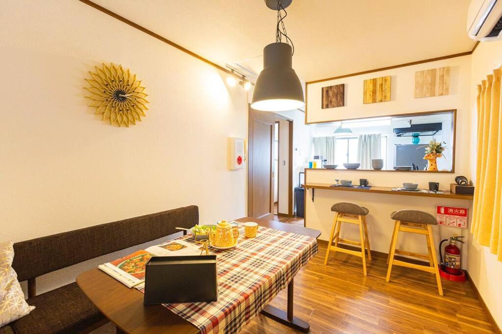 sala de estar con mesa y cocina en 駐車場無料！静かな住宅街　４つの寝室でご家族でゆっくりお過ごし頂けます　7台の寝具で最大11名様まで en Osaka