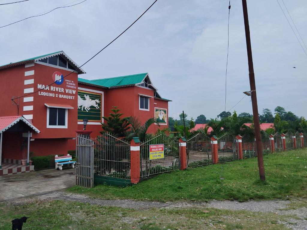 un bâtiment rouge avec une clôture devant lui dans l'établissement Maa River View, à Alīpur Duār