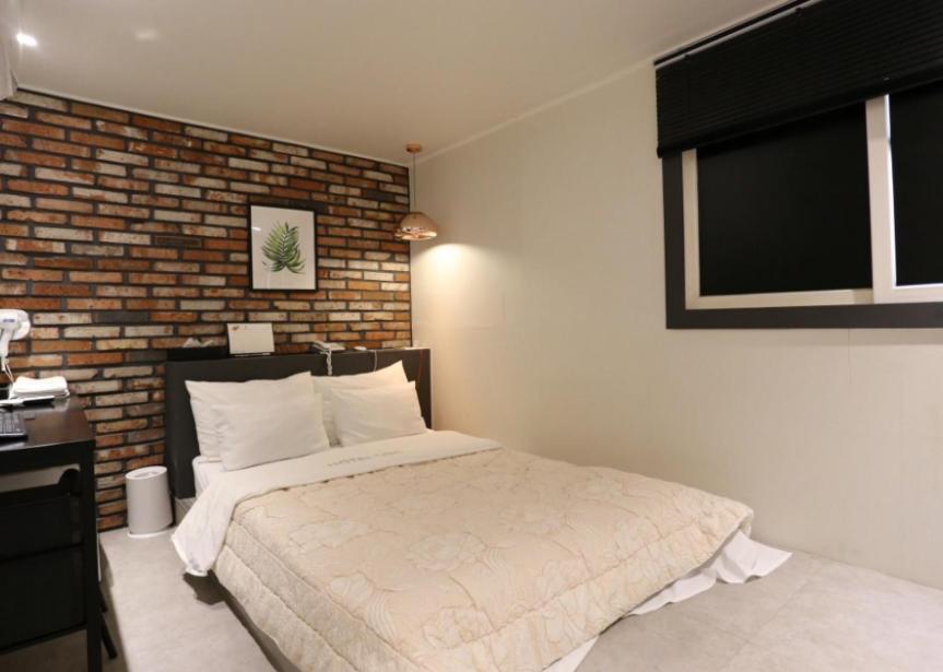 sypialnia z łóżkiem i ceglaną ścianą w obiekcie Hotel Soo w Seulu