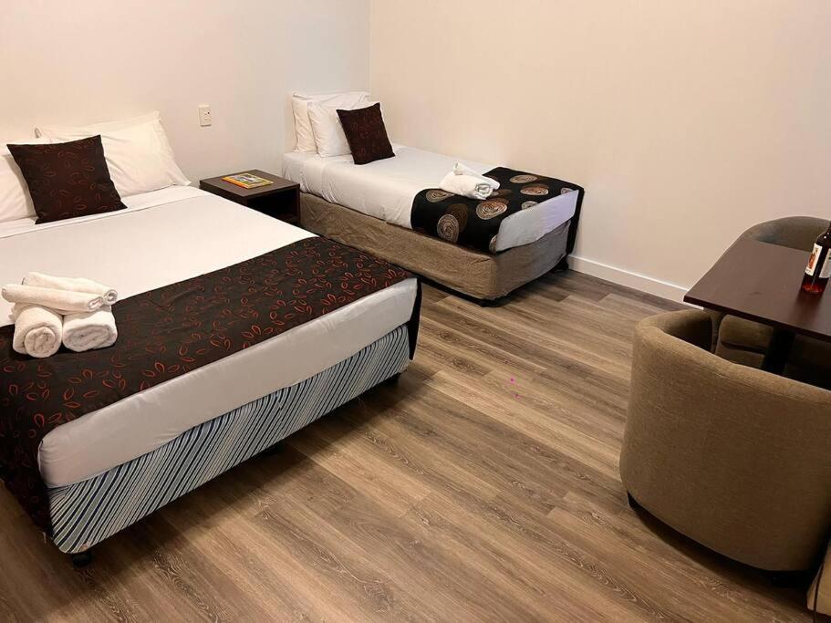 um quarto de hotel com duas camas e uma cadeira em ensuite studio at gouger st 106 em Adelaide