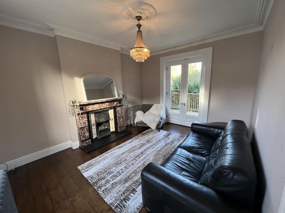 sala de estar con sofá de cuero negro y chimenea en Tranquil Retreat in Historic Chapelizod en Dublín