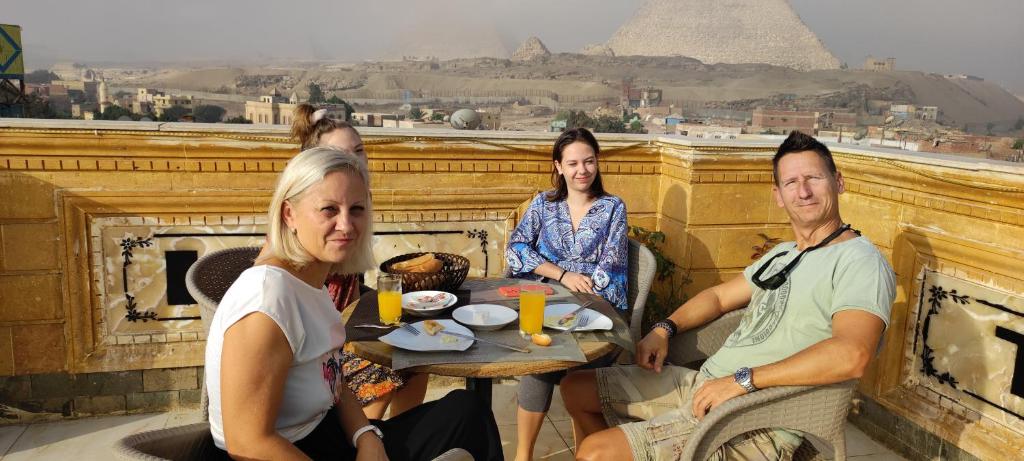 a group of people sitting at a table in front of the pyramid at Pyramids kingdom - guest house in Cairo