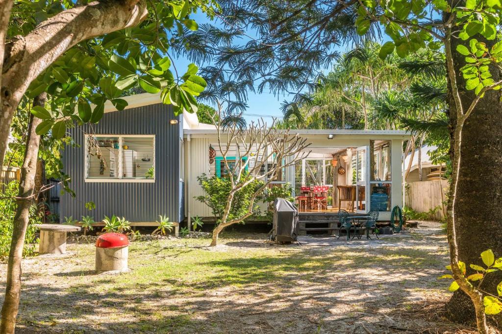 a house with a porch and a yard with trees at A Perfect Stay - Beachcombers Cottage in Suffolk Park