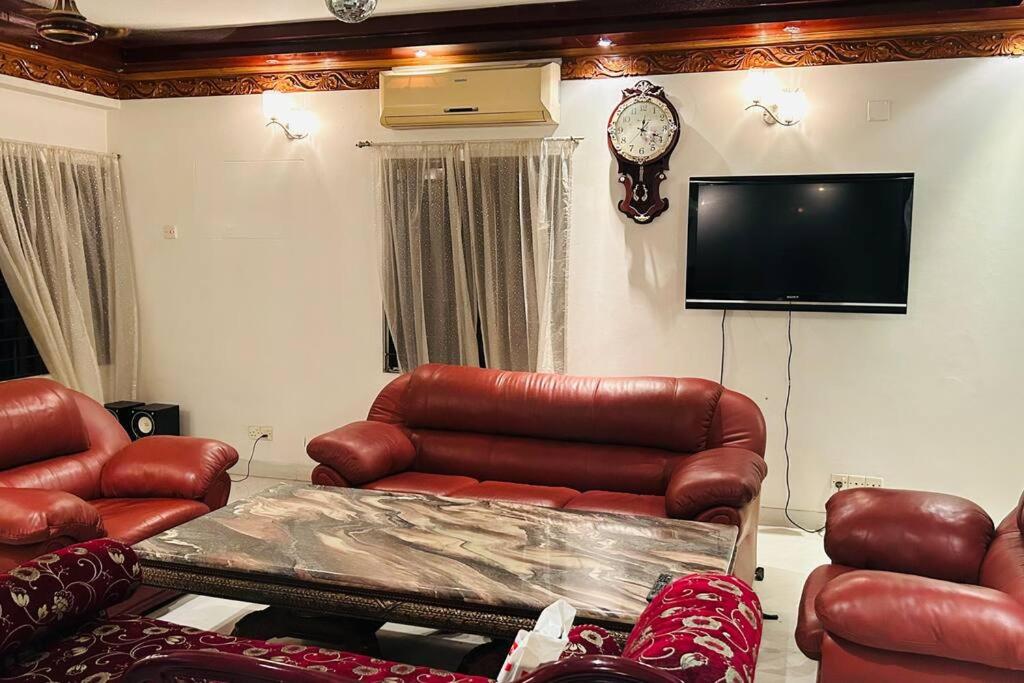 un soggiorno con mobili in pelle e TV a schermo piatto di Oriental Arcadia Elegant Apartment in Gulshan 2 a Dhaka