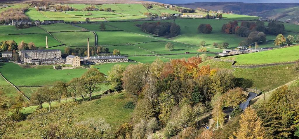 a green field with a building on a hill at Brook Terrace in Luddenden Foot