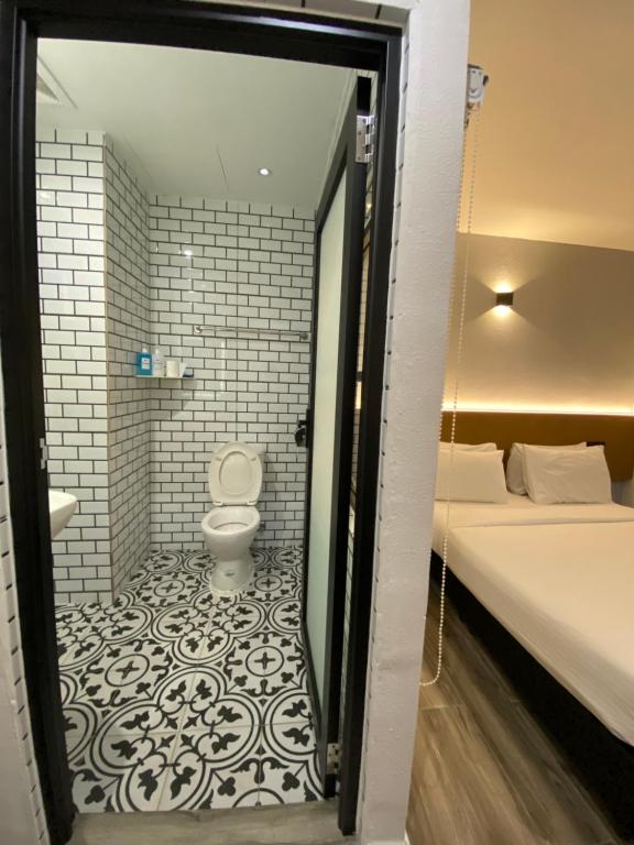 un bagno con servizi igienici e un letto in una camera. di Georgetown Inn by Sky Hive a George Town