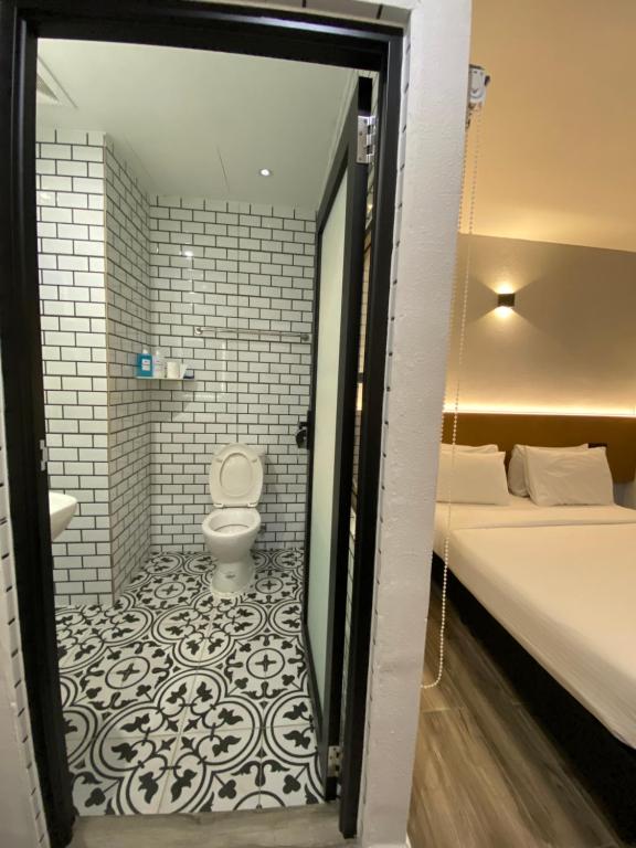 a bathroom with a toilet and a bed in a room at Georgetown Inn by Sky Hive in George Town