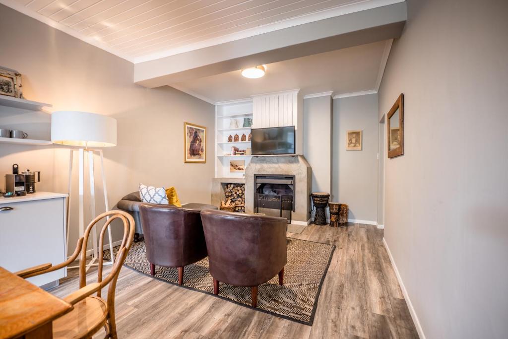 a living room with two leather chairs and a fireplace at The Corner House L'A-nnexe in Franschhoek