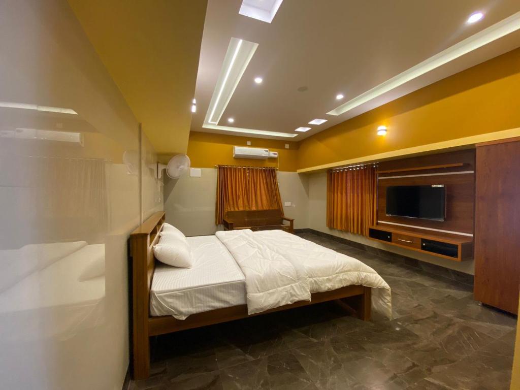 une chambre avec un lit et une télévision à écran plat dans l'établissement Shreesham Resort at Malpe Beach, à Udupi