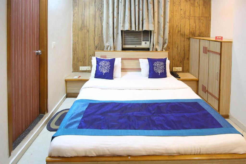 a bedroom with a large bed with blue pillows at Hotel O Liberty in Ahmedabad