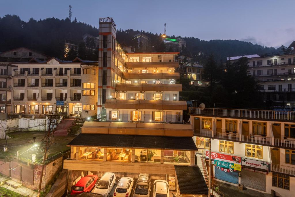 a large building with cars parked in a parking lot at Spring Valley Resorts by DLS Hotels in McLeod Ganj