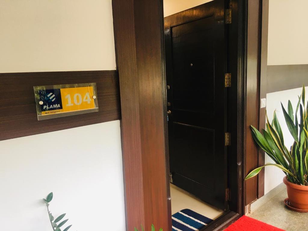 a black door with a sign on it next to a plant at Vaishnavi furnished flats in Mangalore
