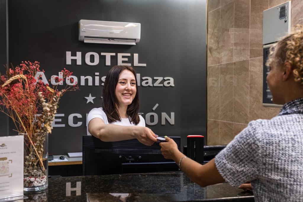a woman holding a remote control in front of a hotel room at Hotel Adonis Plaza in Santa Cruz de Tenerife