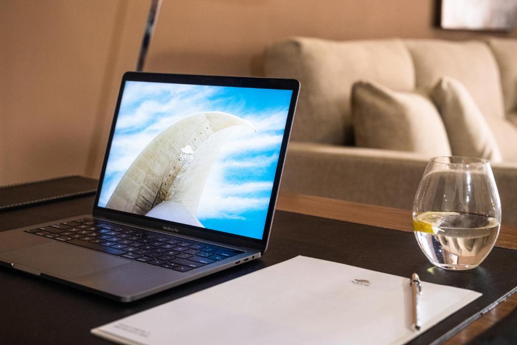 a laptop computer sitting on a table with a glass of wine at Hotel Adonis Plaza in Santa Cruz de Tenerife