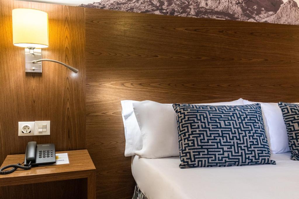 a hotel room with a bed with a lamp and a phone at Hotel Adonis Plaza in Santa Cruz de Tenerife