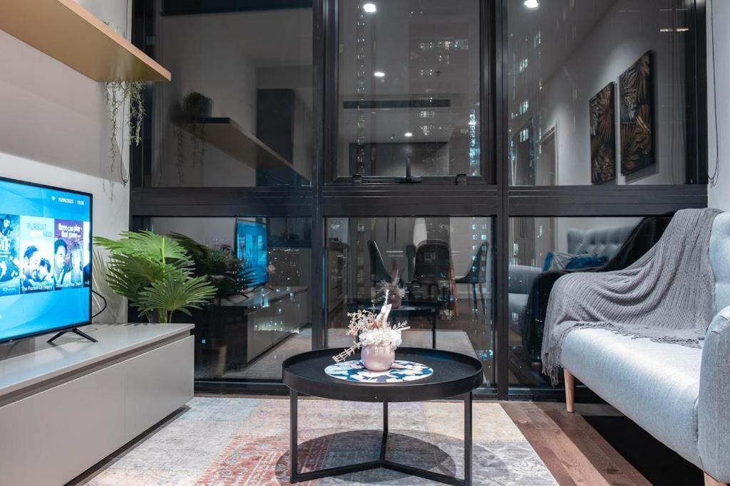uma sala de estar com uma televisão e uma mesa em Relaxed 1br1ba City View Apt Wifi In Cbd em Melbourne