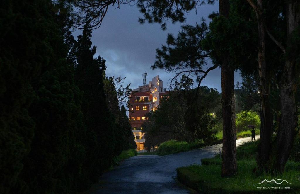 a building in the middle of a road with trees at Mùa Dalat Wellness Hotel in Da Thien