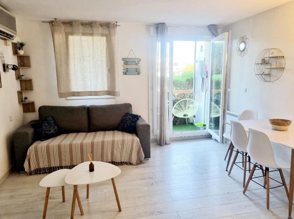 a living room with a couch and a table at 100 m de la plage - Les Cigales de Mer - Studio Cabine - Parking in Le Grau-du-Roi