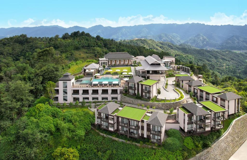 Dusit Thani Himalayan Resort Dhulikhel, Nepal في دهوليكهيل: اطلالة جوية على مبنى فيه جبال في الخلفية