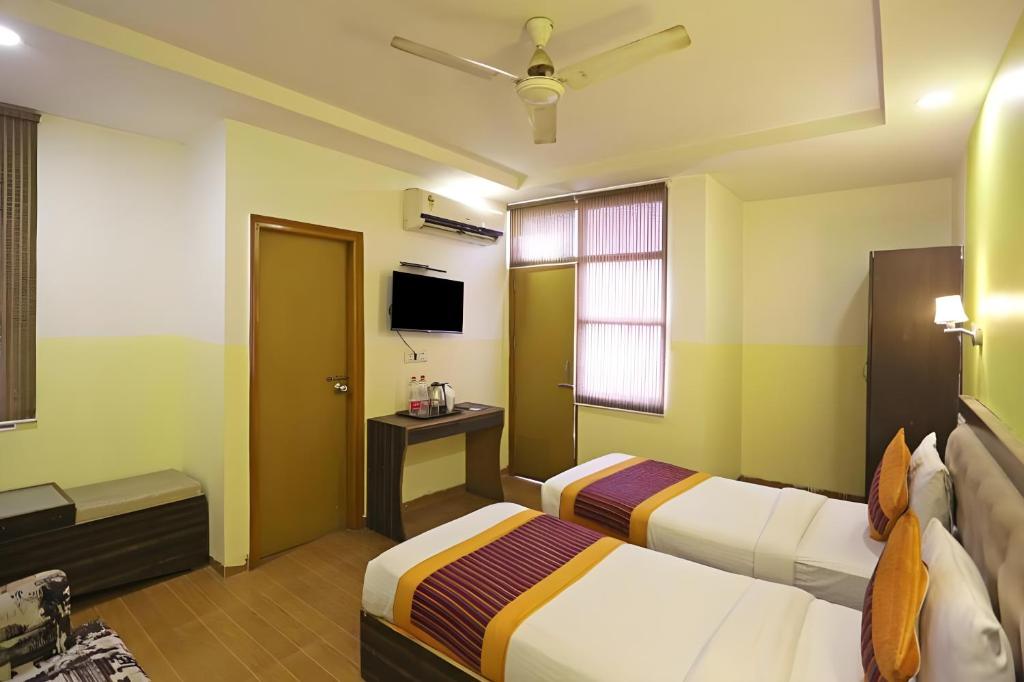 a hotel room with two beds and a tv at Hotel Aeroporto Near By Domestic Airport in New Delhi